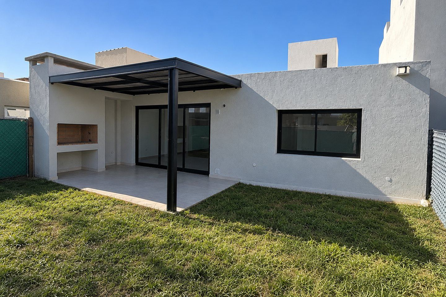 Contrafrente: galería con asador, pérgola y patio con césped
