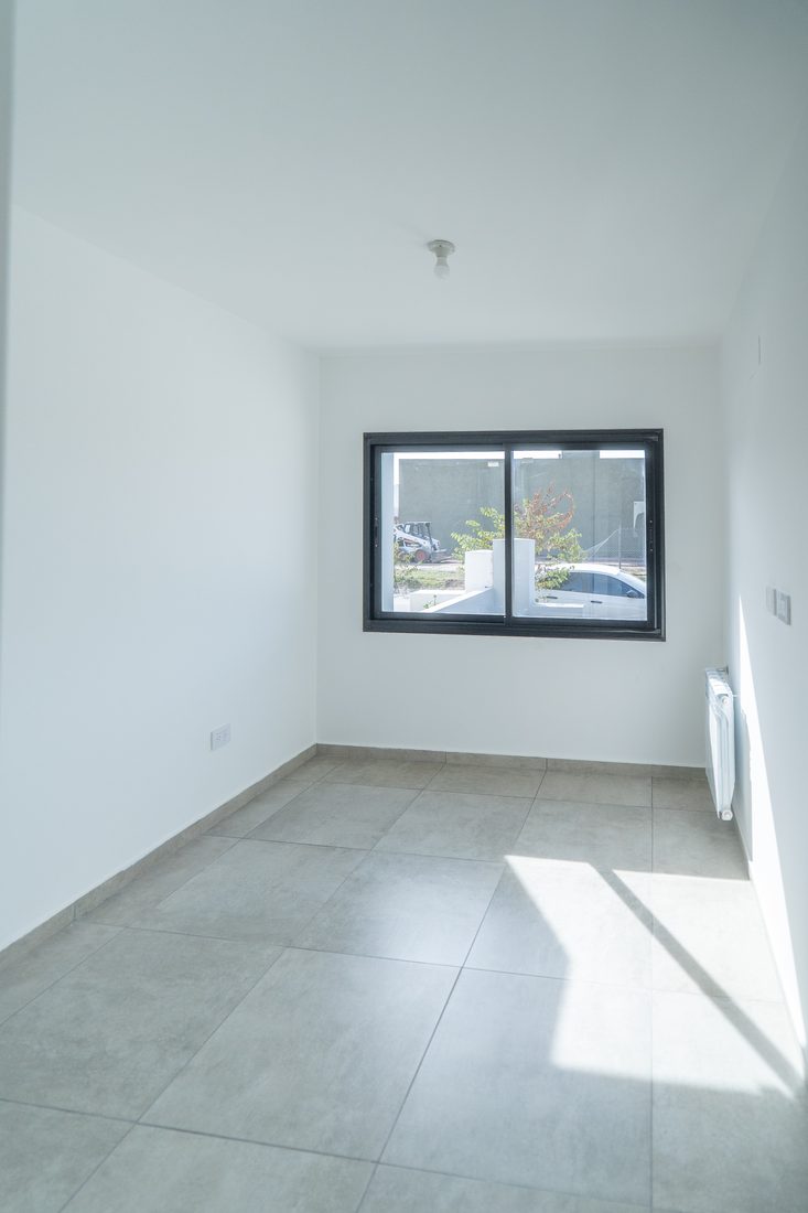 Dormitorio con ventana de aluminio negro y radiador