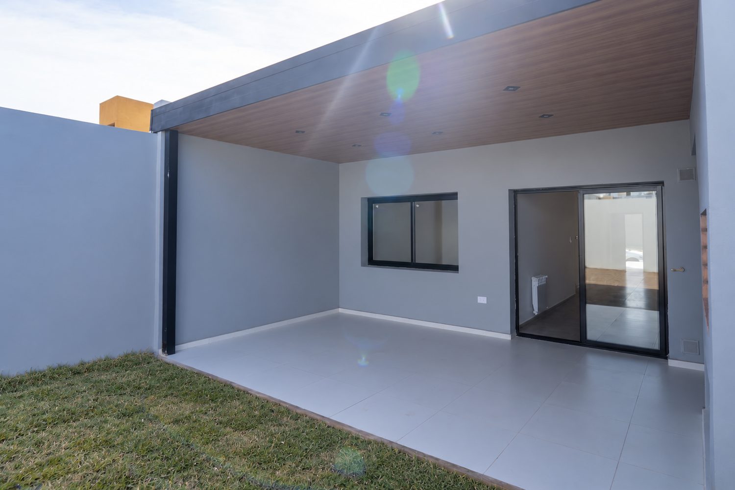 Galería cubierta con cielorraso de madera y acceso al interior