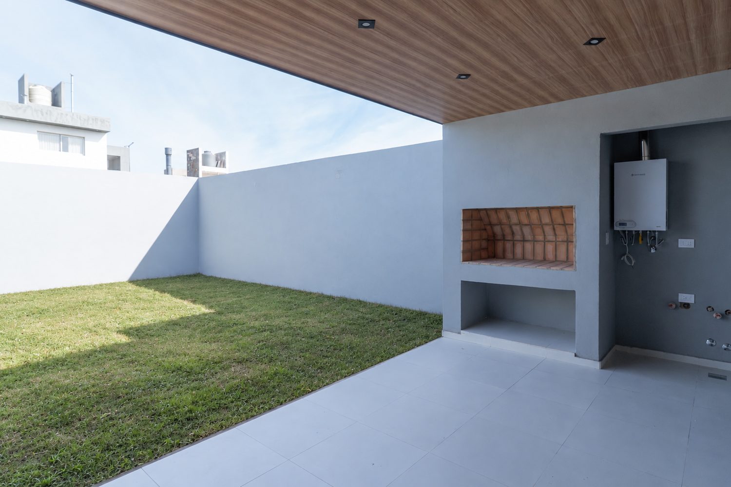 Quincho con cielorraso de madera, parrilla y patio con césped