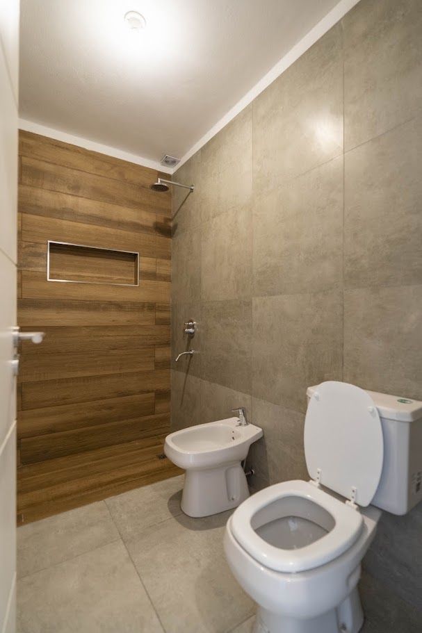 Baño con ducha revestida en porcelanato símil madera, nicho y bidet