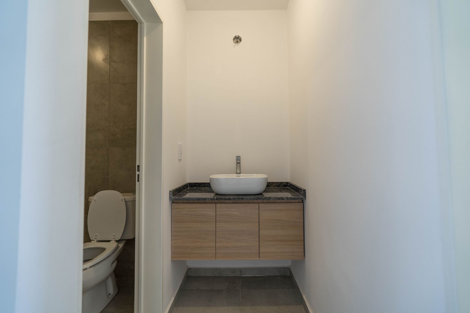 Baño con mueble suspendido y bacha de apoyo sobre granito